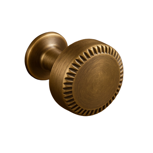 A round brass cabinet knob with a textured, sunburst-style edge and a brushed finish, mounted on a dark brown wood surface.