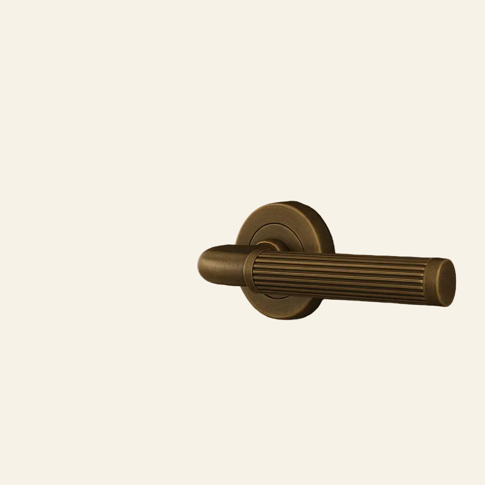 Close-up of a bronze door handle on a wooden door with a blurred living room in the background.