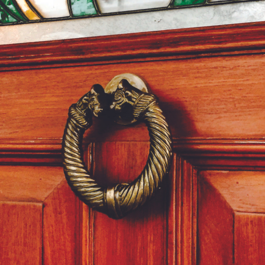 AceLine Brass door knocker on a wooden door with stained glass above